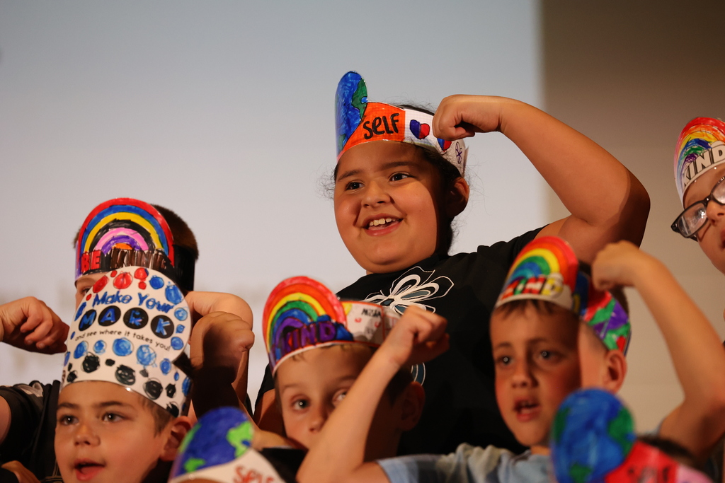 student sings and does a muscle pose during a performance