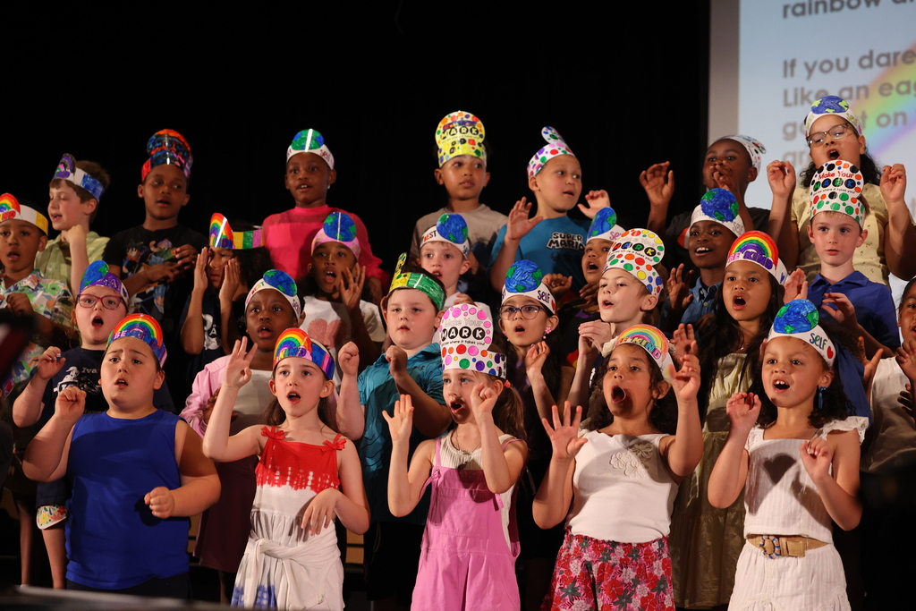 students sing on stage while doing dance moves