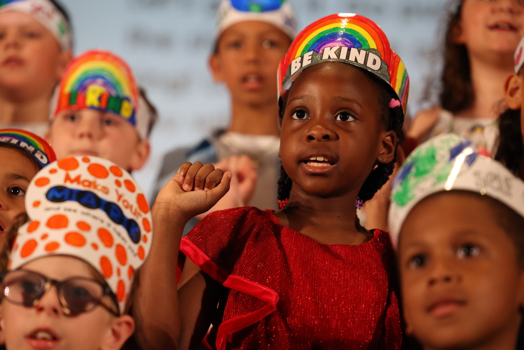 student sings on stage with a be kind crown