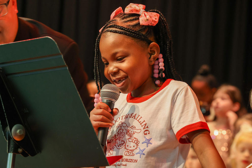 student smiles and speaks into the microphone on stage