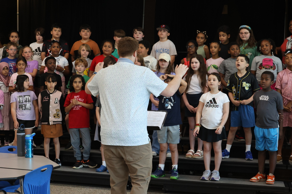 large group shot of the chorus group and instructor conducting them