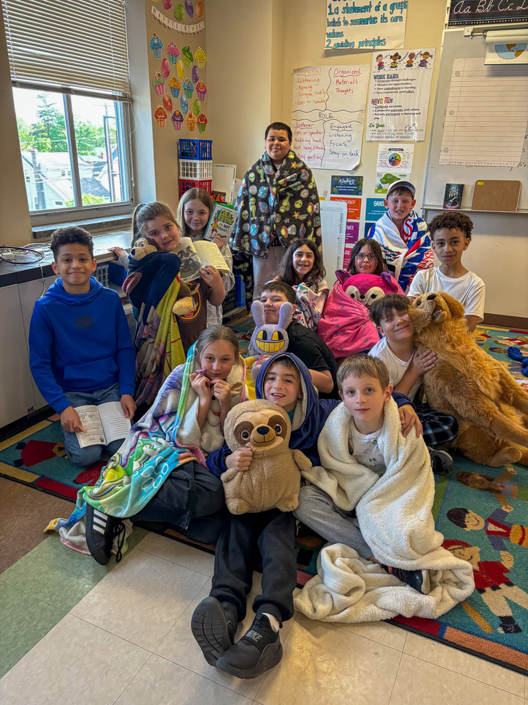 students smile with stuffed animals and blankets in classroom