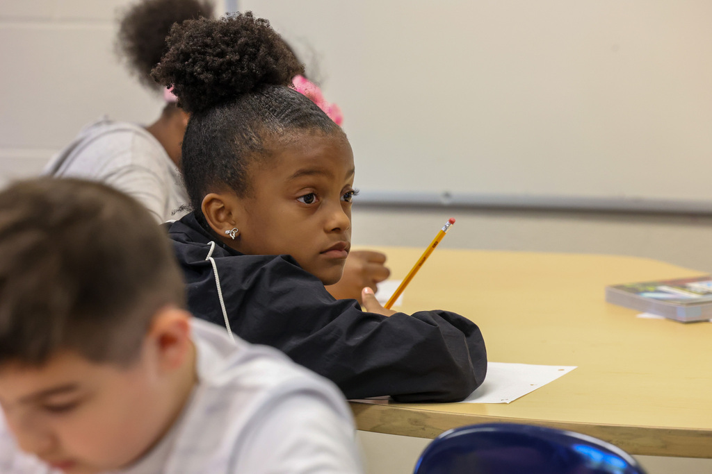 student writes with pencil and looks up a presenter