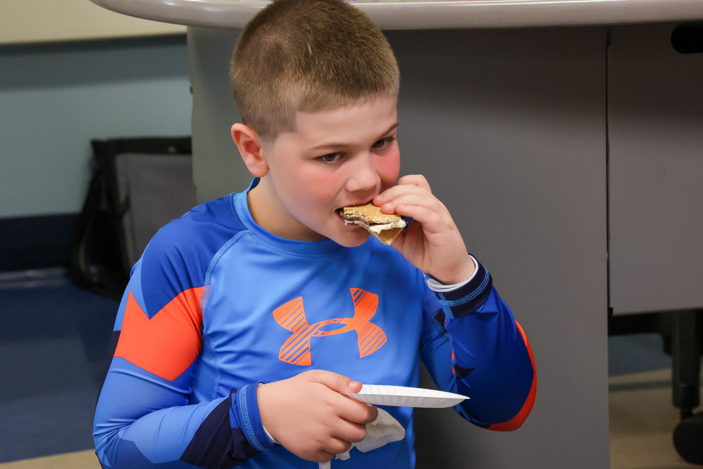 student enjoys smore snack in a blue shirt 
