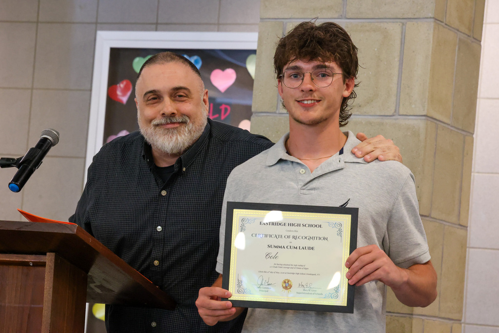 student and staff member smile and pose for the camera with certificate of recognition