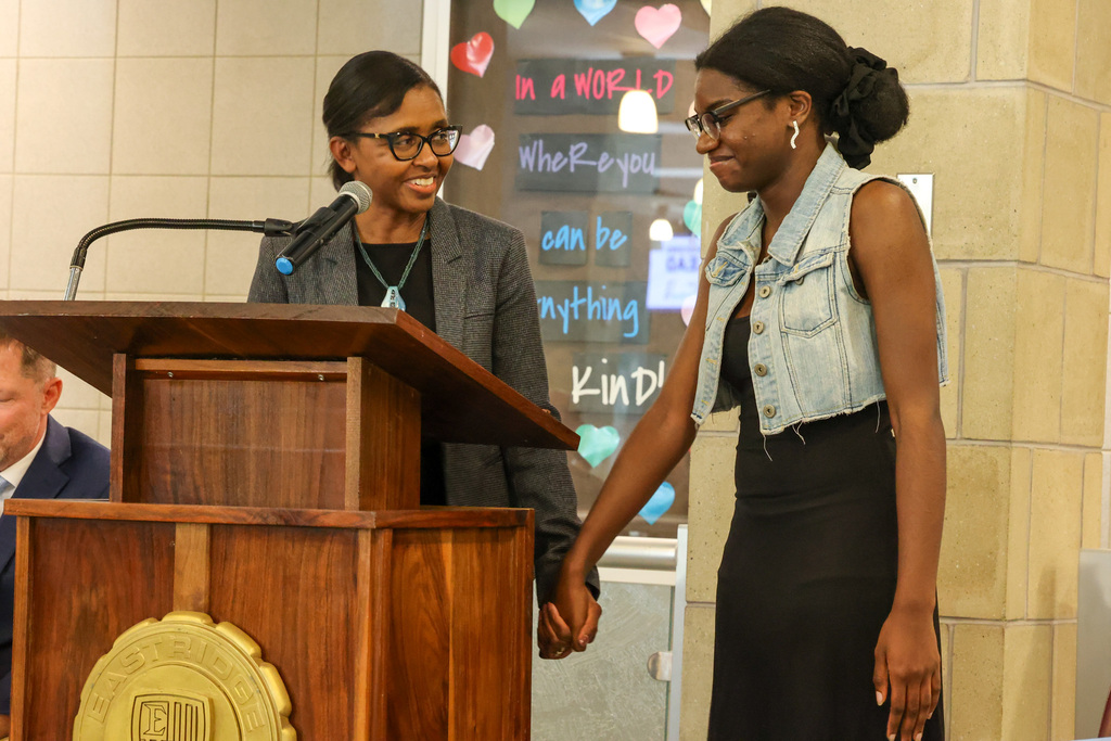 Student and staff member hold hands with at podium