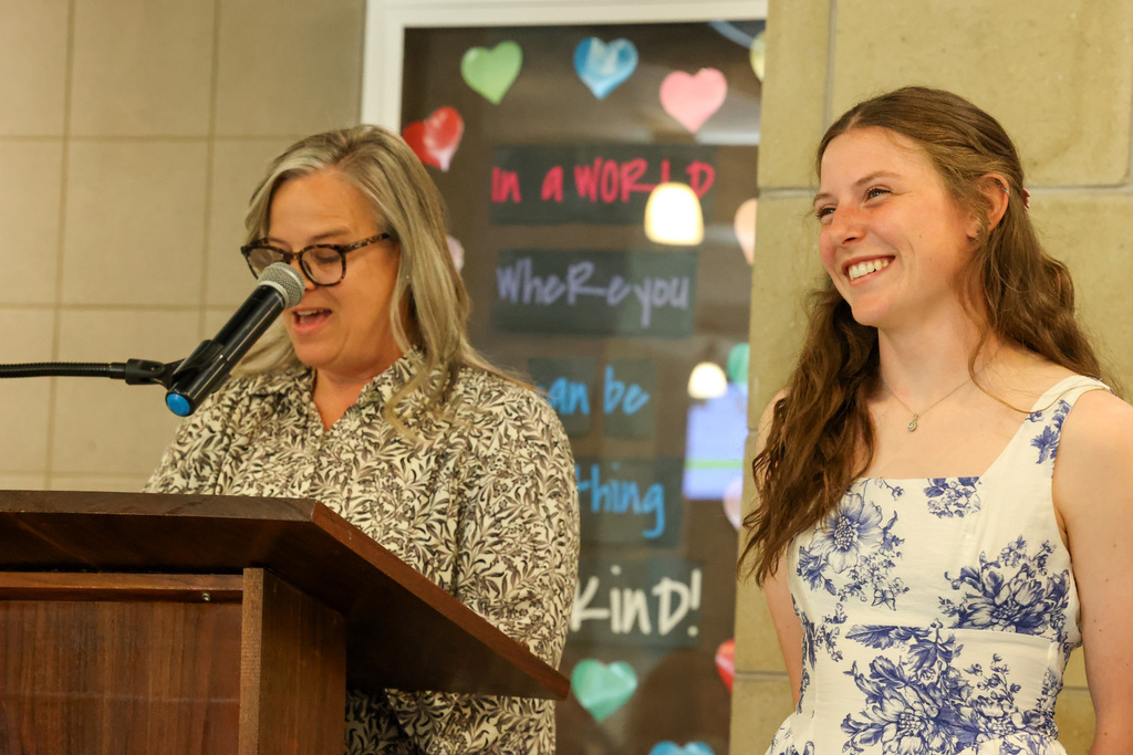 Student smiles while staff member reads at microphone 