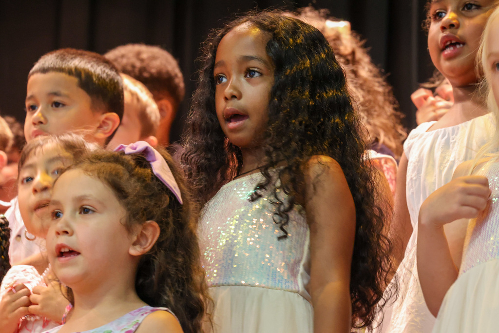 student sings in a white glitter dress on stage