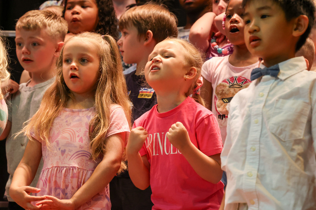 Students sings and holds hands in fists on stage