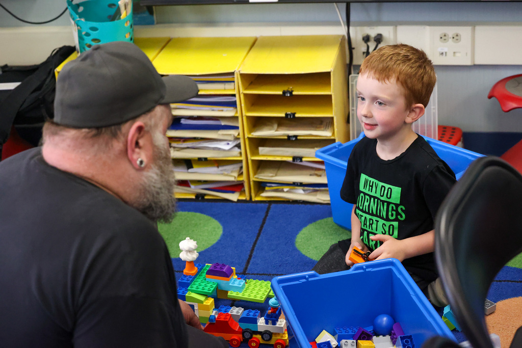 child and parent play legos while he looks at him