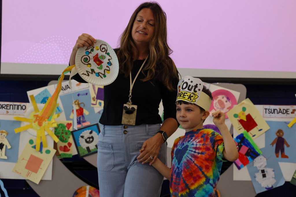 student stands with teacher holding award