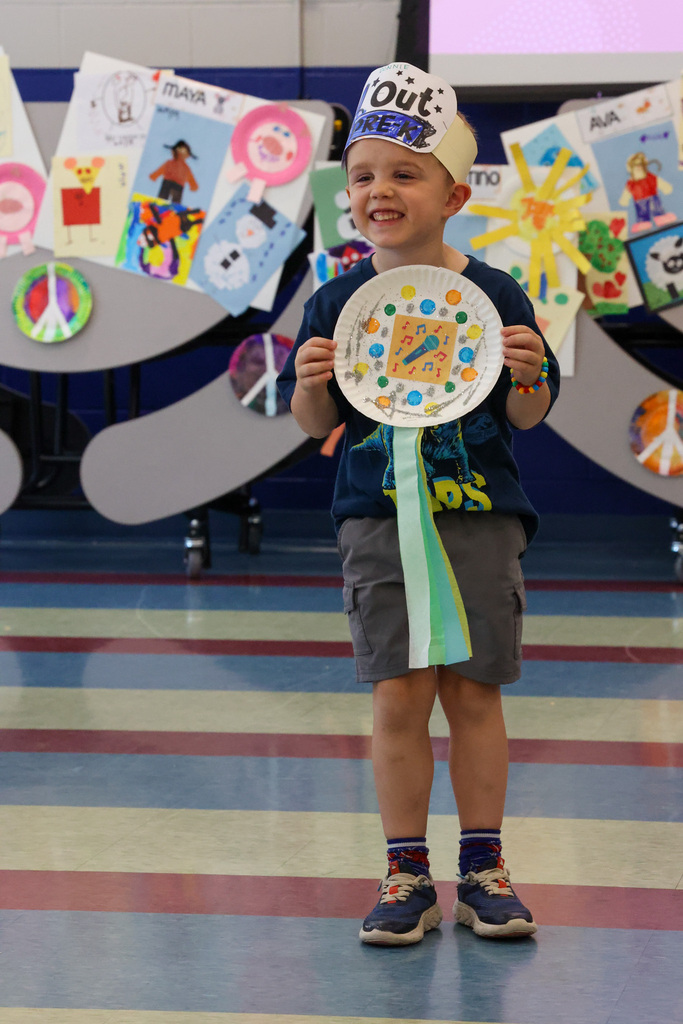 Student holds up paper plate award and smiles