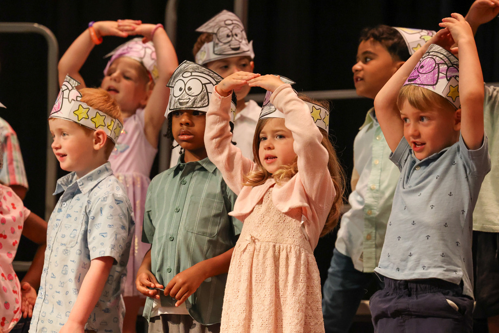 Students dance and wear graduation headbands in pre k