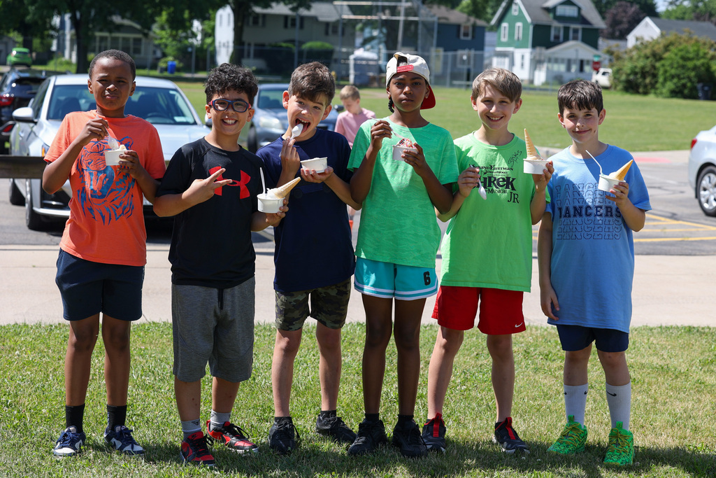 group of boys hold up ice cream outside 