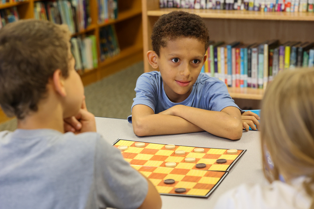 Student plays checkers with friends