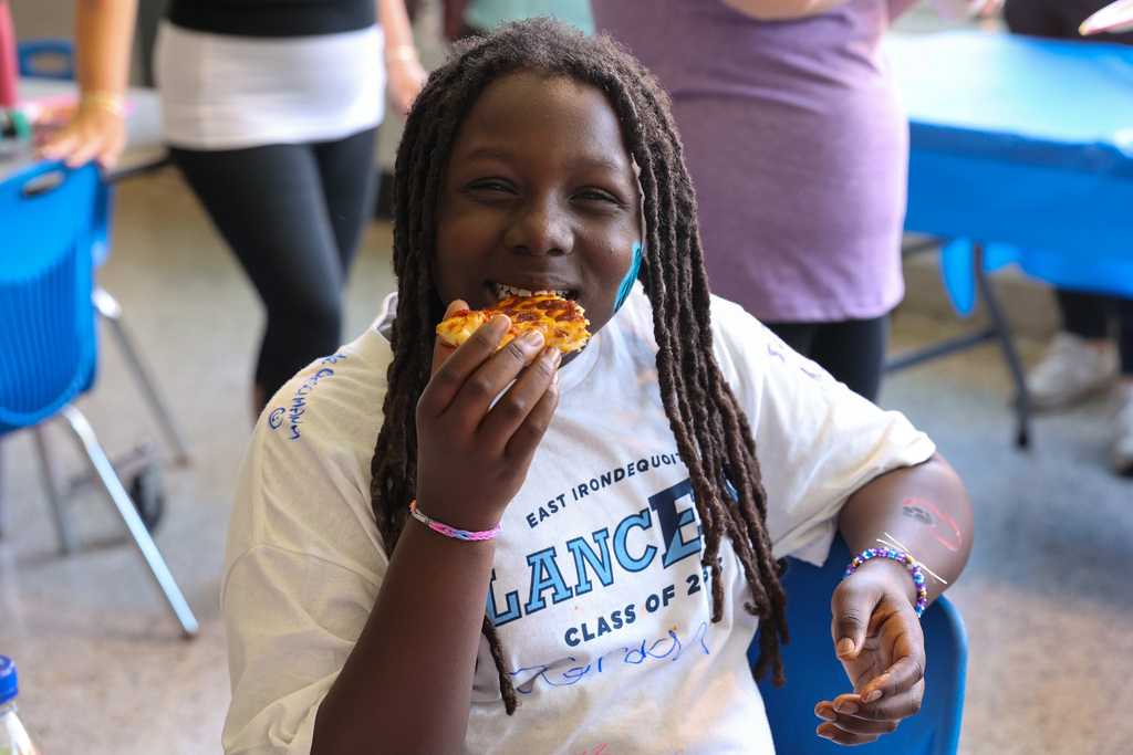 students takes a bite of pizza and smiles