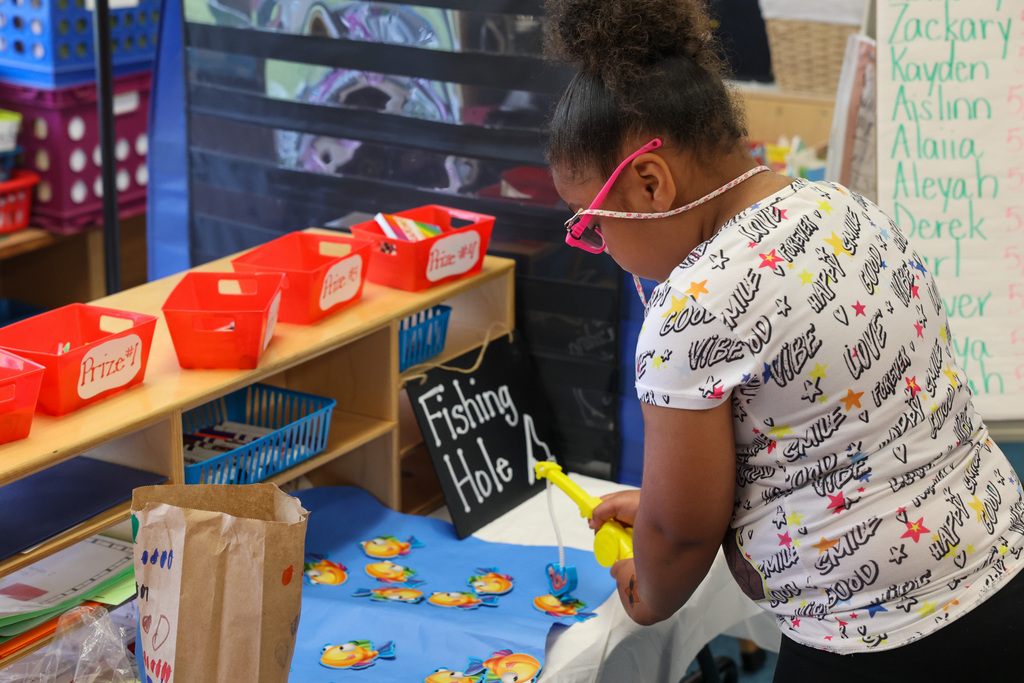 student does fishing hole game at carnival in classroom