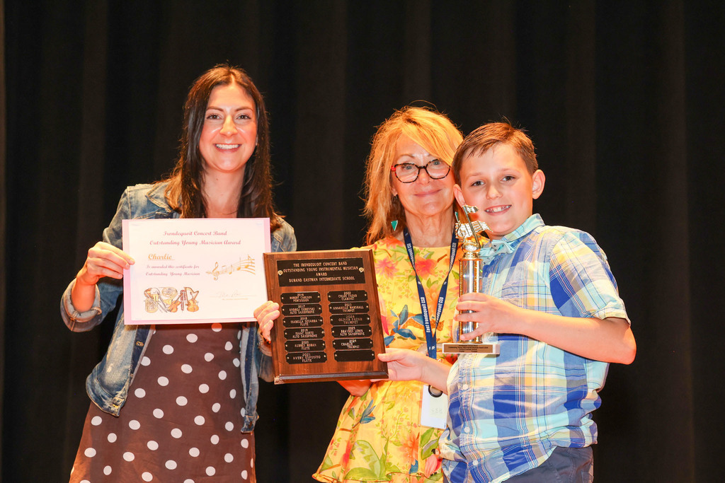 Teacher and principal hold up awards with student