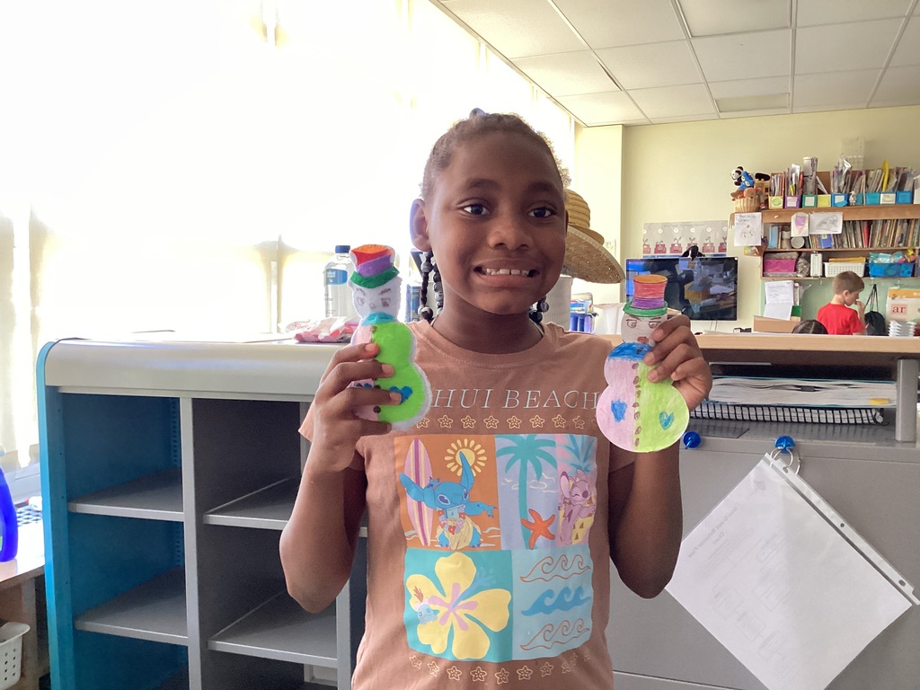 students holding their drawing and sewing project