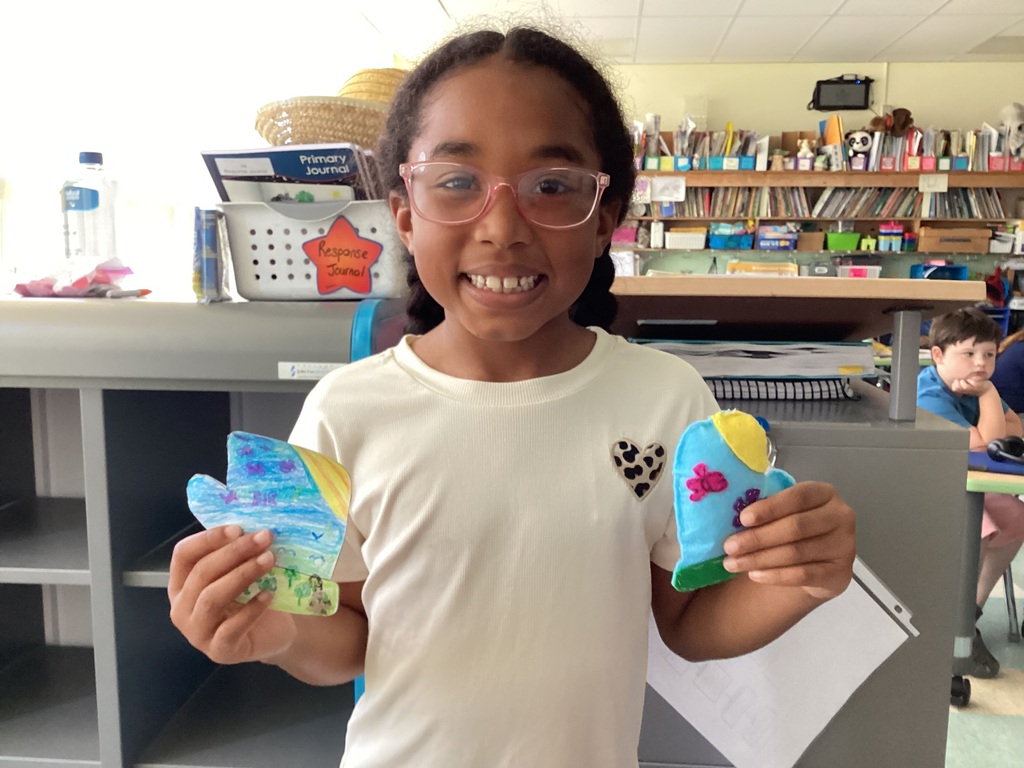 students holding their drawing and sewing project