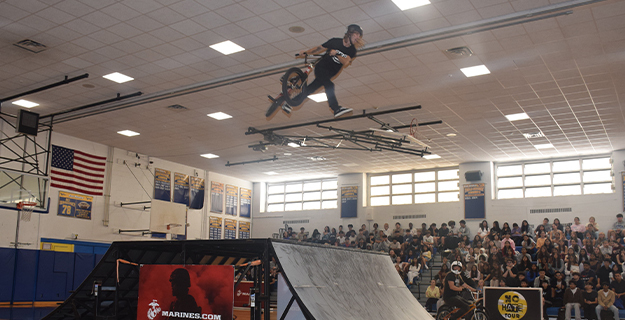 BMX professional doing tricks in gymnasium.