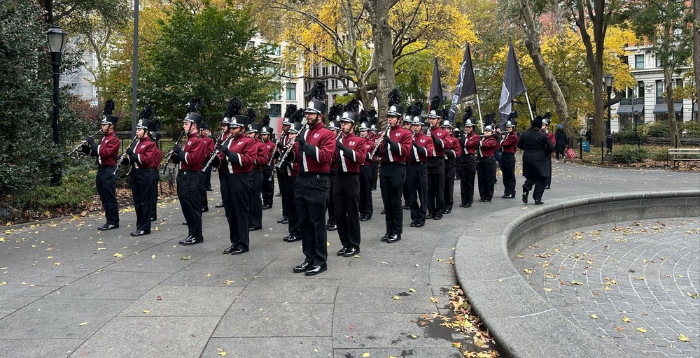 A marching band in red uniforms practices in