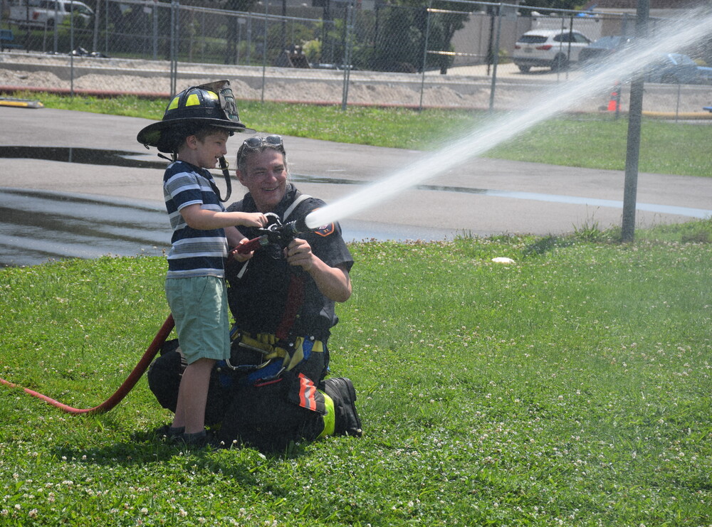 Student shooting hose with firefighter.