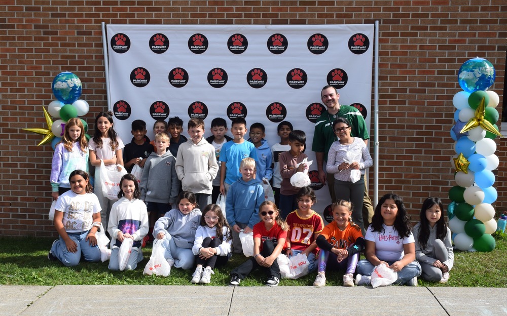 students in a group photo outside of the school against the wall with a white banner