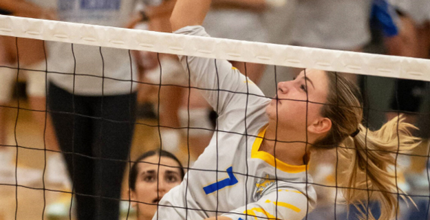 Female volleyball player hitting volleyball.