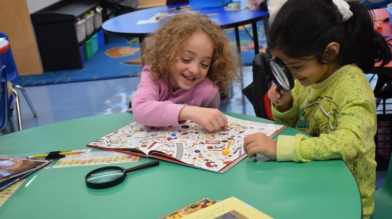  sitting with at a round table covered with educational materials and crafts, conveying a cheerful learning atmosphere.