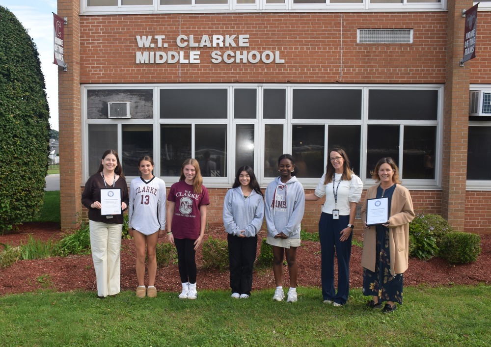 Students and teachers holding certificate outside school.