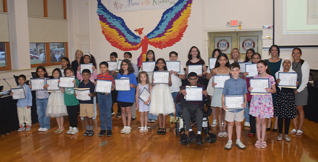 Students holding awards, smiling with teachers behind them.