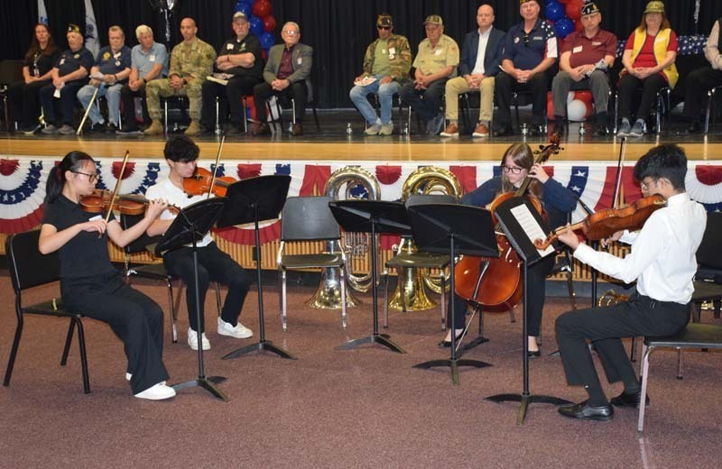 Photo of students receiving American flags from local veterans on stage.