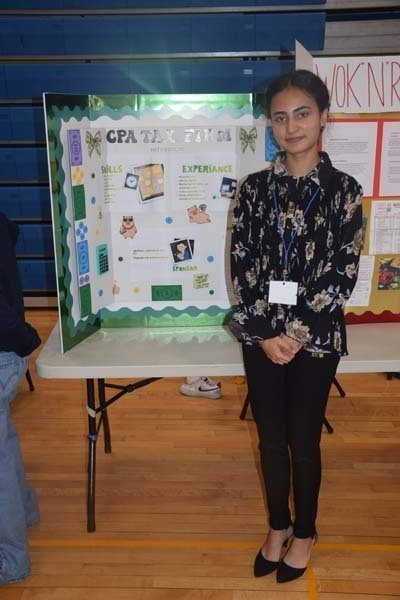 Photo of one high school student standing next to poster boards that she created depicting their future careers for their Senior Project Fair.
