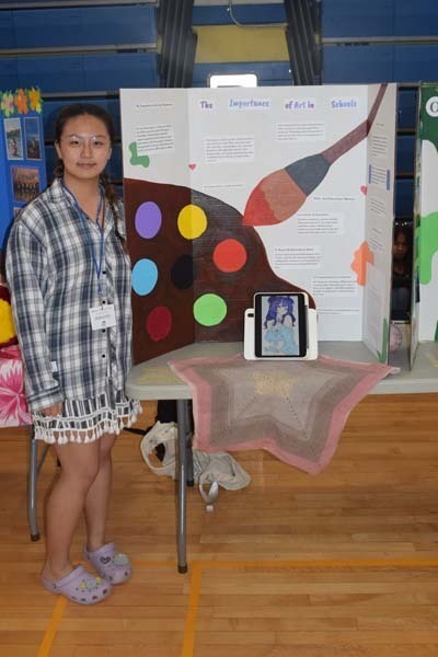 Photo of one high school student standing next to poster boards that she created depicting their future careers for their Senior Project Fair.