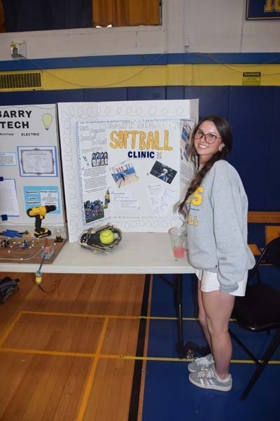 Photo of one high school student standing next to poster boards that she created depicting their future careers for their Senior Project Fair.