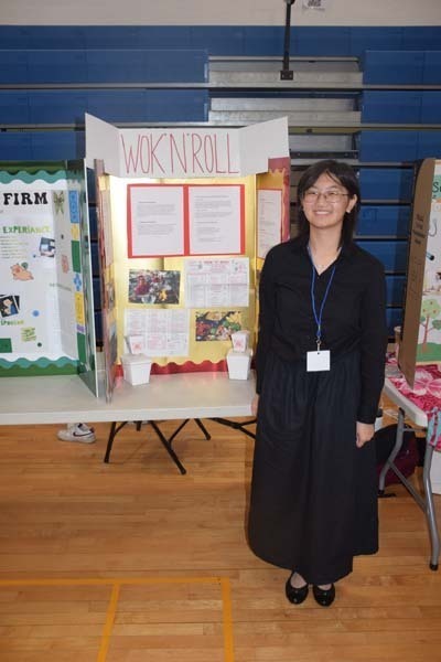 Photo of one high school student standing next to poster boards that she created depicting their future careers for their Senior Project Fair.