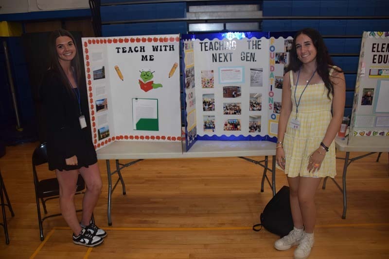 Photo of one high school student standing next to poster boards that she created depicting their future careers for their Senior Project Fair.