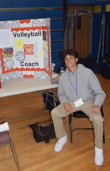 Photo of one high school student standing next to poster boards that she created depicting their future careers for their Senior Project Fair.
