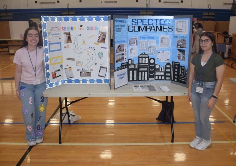 Photo of one high school student standing next to poster boards that she created depicting their future careers for their Senior Project Fair.