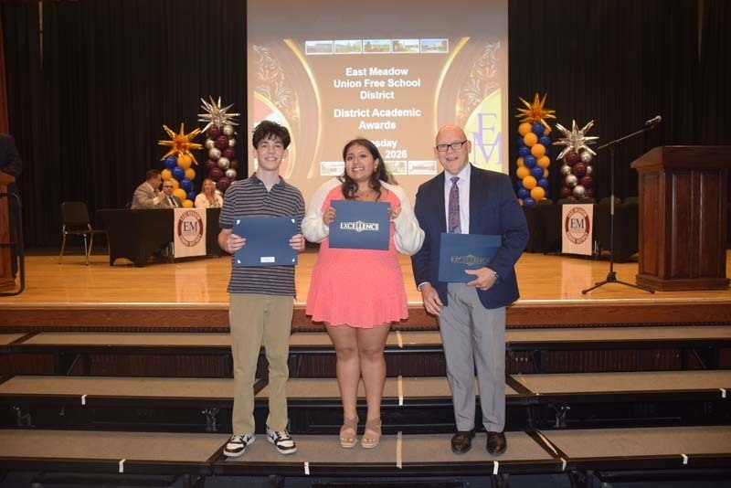 Photo of students standing on risers while holding certificates, medals and awards for their excellence in academics, athletics, clubs and community service.