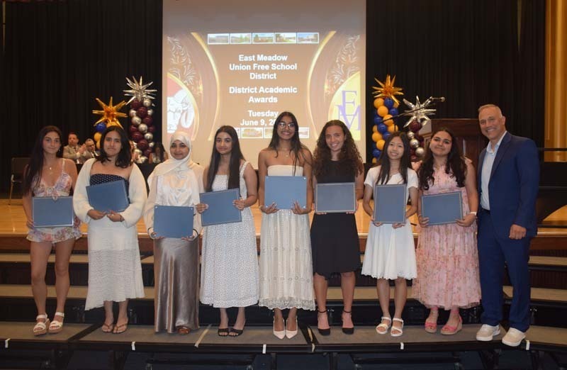 Photo of students standing on risers while holding certificates, medals and awards for their excellence in academics, athletics, clubs and community service.