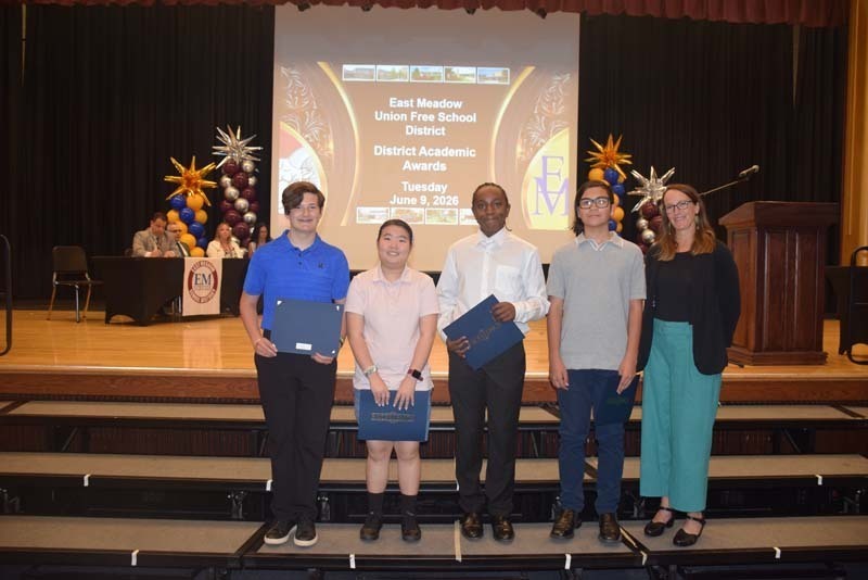 Photo of students standing on risers while holding certificates, medals and awards for their excellence in academics, athletics, clubs and community service.