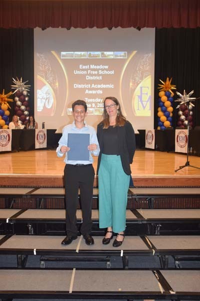 Photo of students standing on risers while holding certificates, medals and awards for their excellence in academics, athletics, clubs and community service.