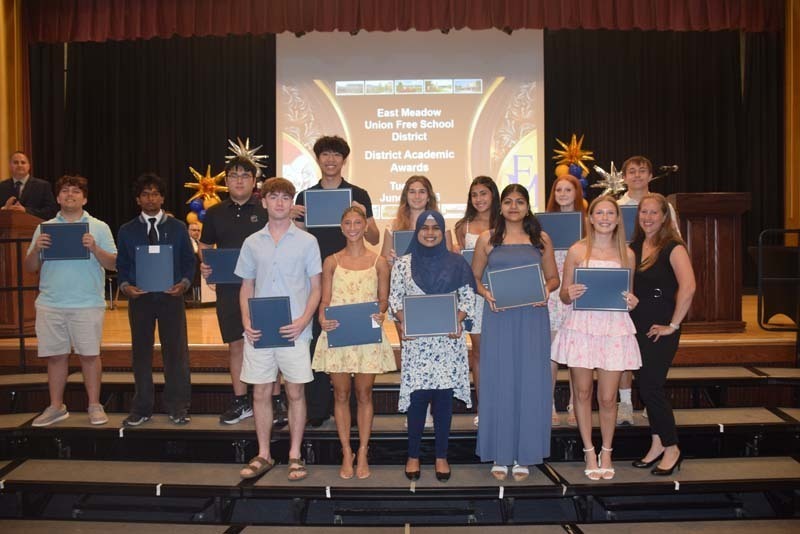 Photo of students standing on risers while holding certificates, medals and awards for their excellence in academics, athletics, clubs and community service.