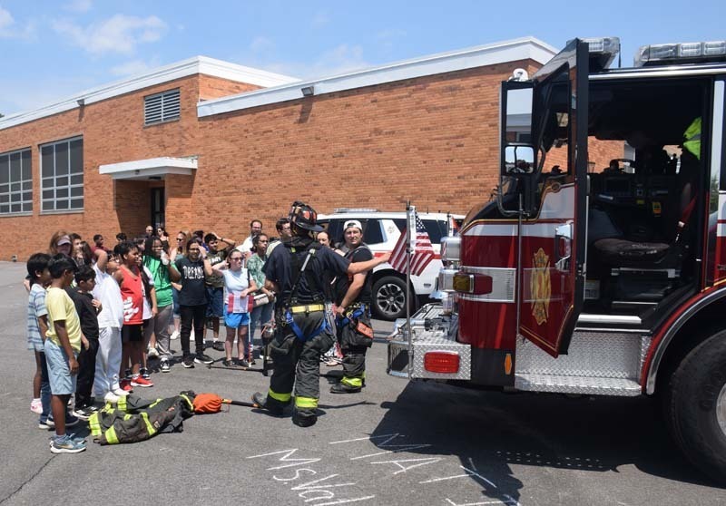 Firefighter talking to students outside.