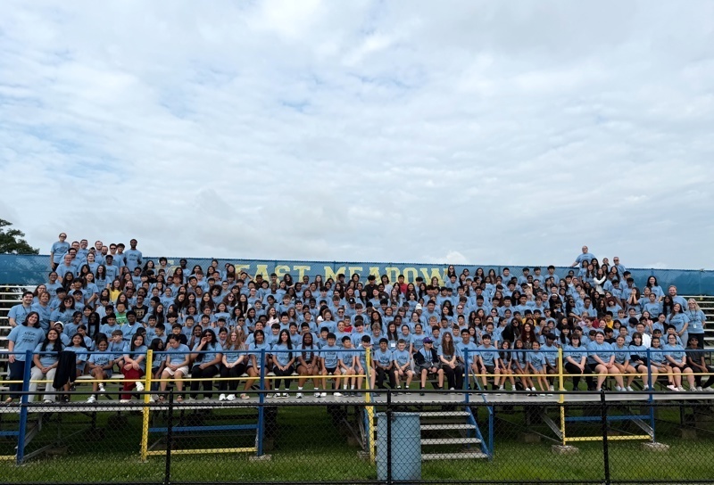 large group on bleachers wearing blue shirts