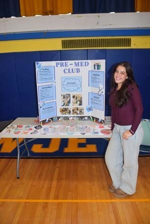 Photo of high school students with posterboard of their club.