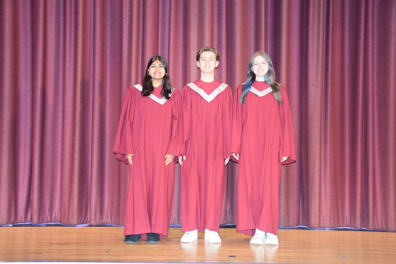 A group of people standing together on stage in front of a curtain backdrop.