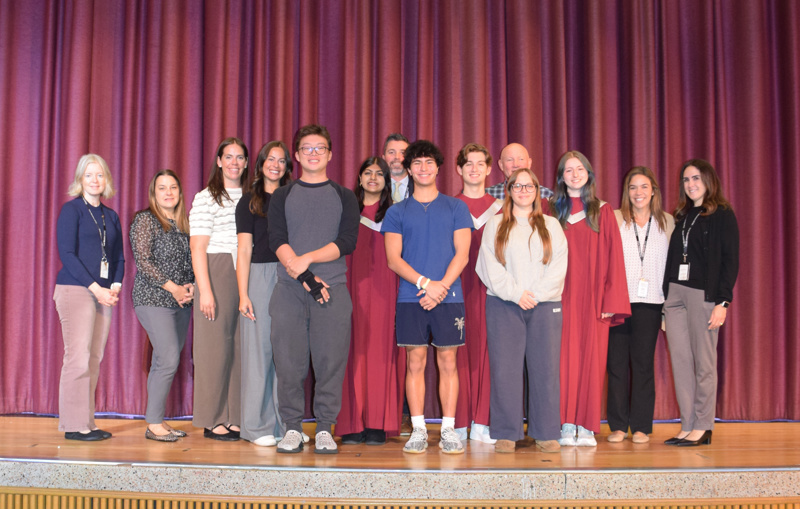 A group of people standing together on stage in front of a curtain backdrop.